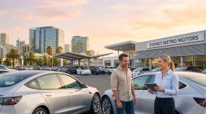 A man and a saleswoman with a tablet talking at a Sydney Metro Motors dealership during sunset.